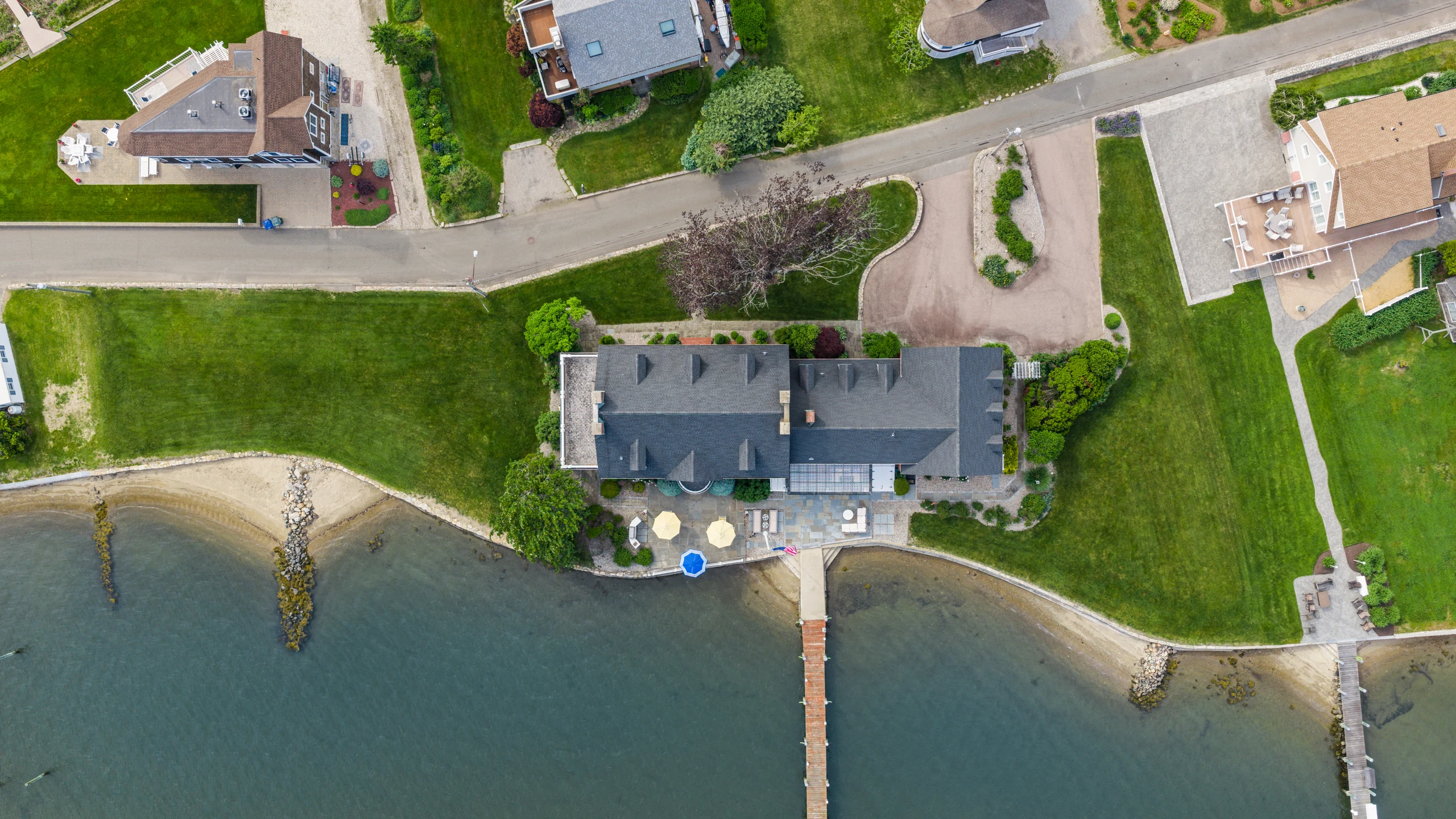 Overhead aerial view of the lawn, beach, and dock reaching into the water.