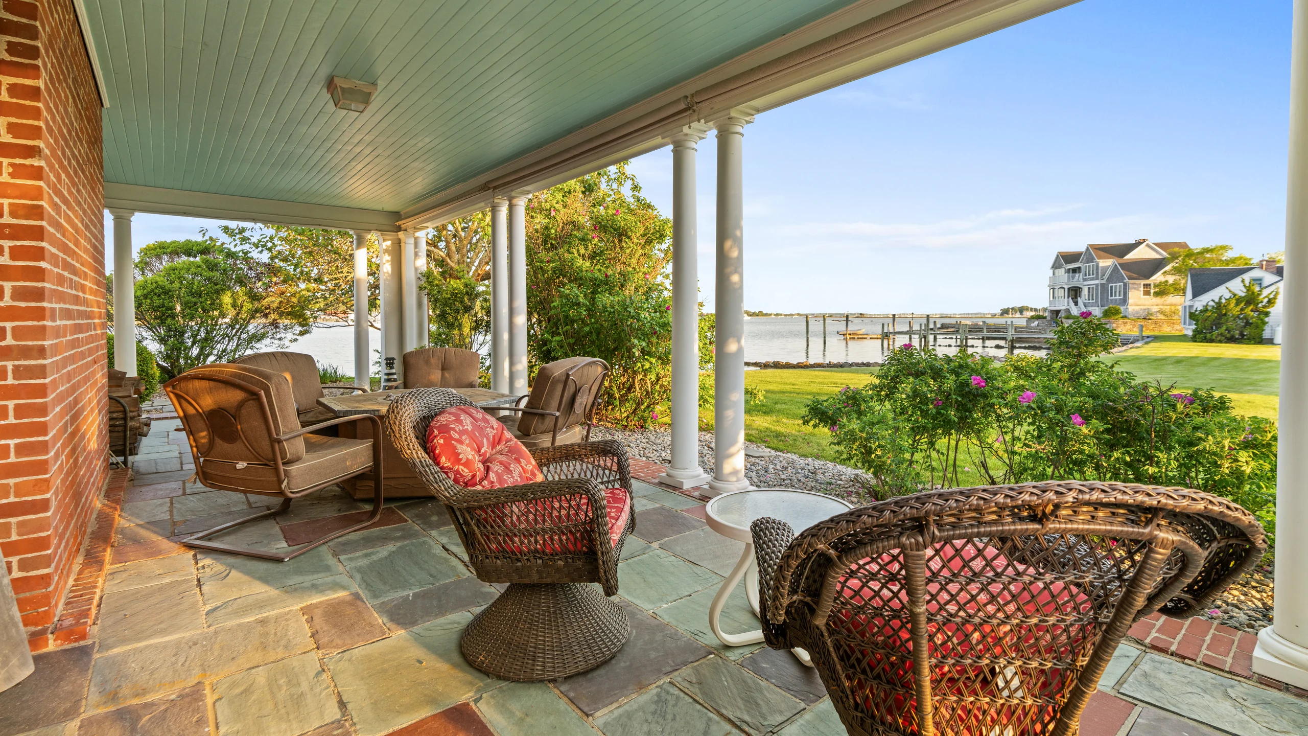 Covered porch seating looking out toward the lawn, dock, and water.