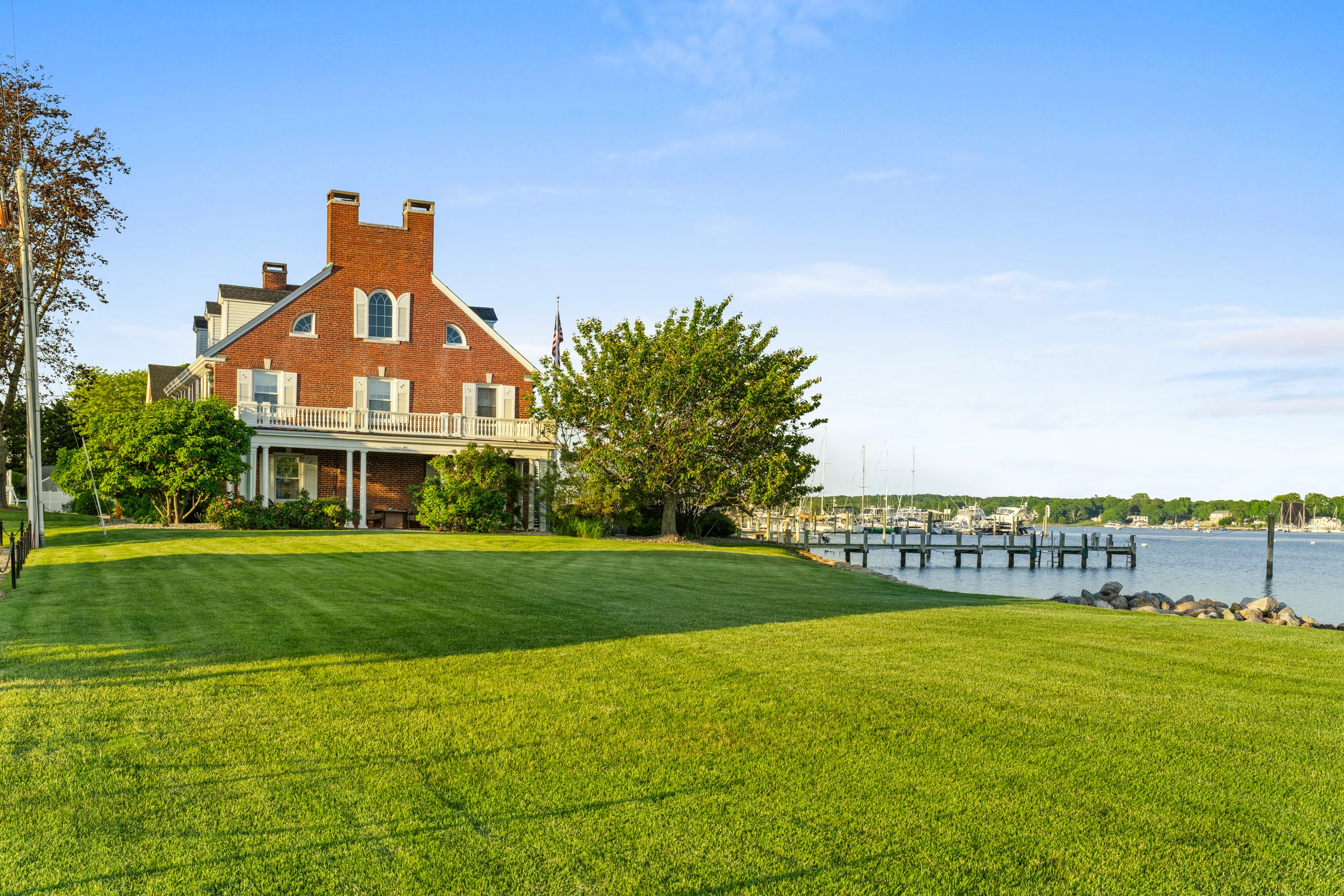 The brick Georgian Colonial seen across the broad lawn toward the dock and water.